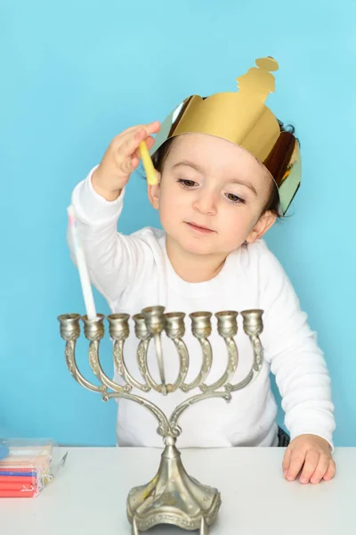 Kleine joodse jongen zet kaarsen op traditionele menorah. — Stockfoto