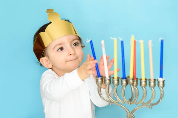 Kleiner jüdischer Junge stellt Kerzen auf traditionelle Menora. — Stockfoto