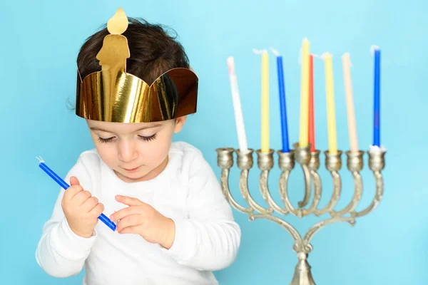 Little jewish boy puts candles on traditional menorah. — Stock Photo, Image