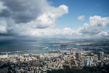 Hayfa İsrail, 15 Mart 2024 Hayfa, İsrail 'in çarpıcı manzarasının tadını çıkarıyor. Kıyı şeridinde dramatik bulutlar ve kentsel manzaralarla çevrili tekneler ve nakliye faaliyetleri yer alıyor..