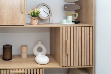 Organize bir rafta modern dekorların, doğal elementlerin ve şık aksesuarların minimalist bir tasarımla harmanlanmış bir karışımı, davetkar ve sakin bir atmosfer yaratıyor..