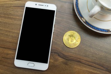 Bitcoin sikke ve Smartphone, Kalem ve Kahve fincan eski ahşap masada