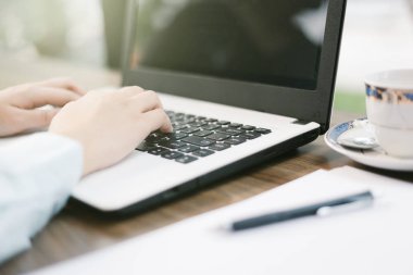 Dizüstü bilgisayar ile çalışan iş kadın yakın çekim arka plan gibi kahve dükkanında bir not belgesi ve akıllı telefon yapmak.