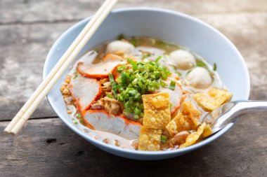 Ahşap arka planda beyaz kase et ile Tay noodle çorbası yakın çekim.