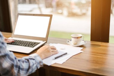 Arka plan gibi kahve dükkanında boş beyaz ekran, akıllı telefon ve belge ile Laptop ile çalışan işadamı yakın çekim.