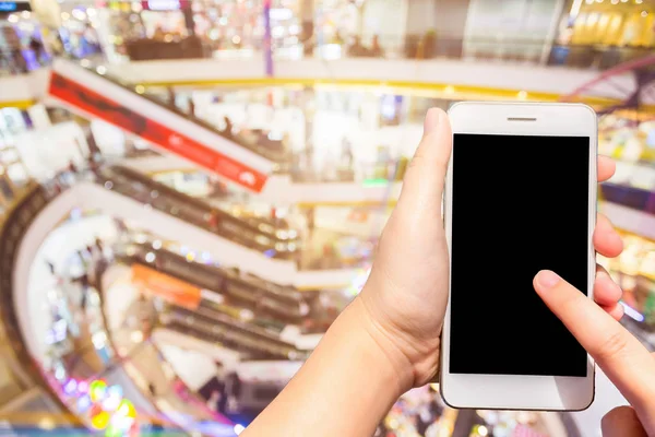 Uso femenino teléfonos celulares imágenes borrosas fondo del centro comercial . — Foto de Stock