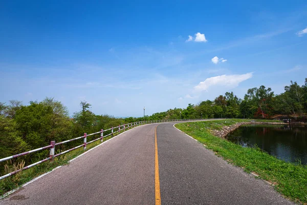 Road view pohon hijau waduk dan latar langit biru . — Stok Foto