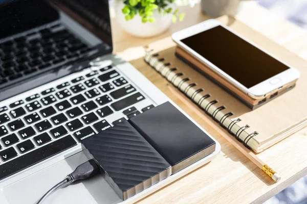 Laptop Klavyesindeki Harici Disk. Not defterinde akıllı telefon var.