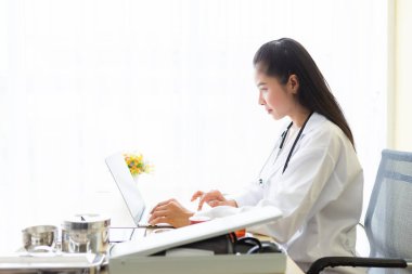 Asyalı genç bayan doktor kollarını steteskopla bağlıyor.