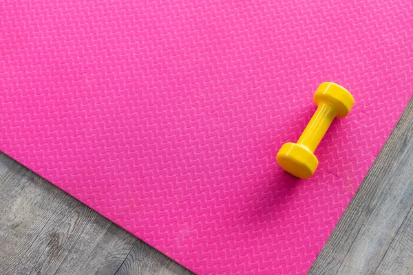 Ahşap döşemede, boş pembe kauçuk zeminde dambıllar.