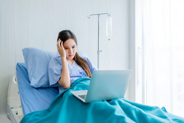 아시아인젊은 환자는 침대에 이있고 배경에는 컴퓨터가 있습니다 시간에 일하는 개념이죠 — 스톡 사진