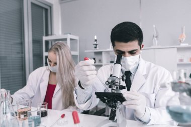 İki bilimadamı test tüpünü incelemek için kimya laboratuvarında çalışan bir bilim adamı ya da genç kadın ve erkek araştırmacı laboratuvar analizinde araştırma yapıyor.