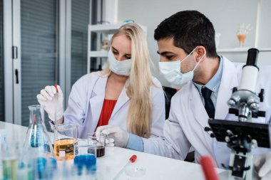 İki bilimadamı test tüpünü incelemek için kimya laboratuvarında çalışan bir bilim adamı ya da genç kadın ve erkek araştırmacı laboratuvar analizinde araştırma yapıyor.