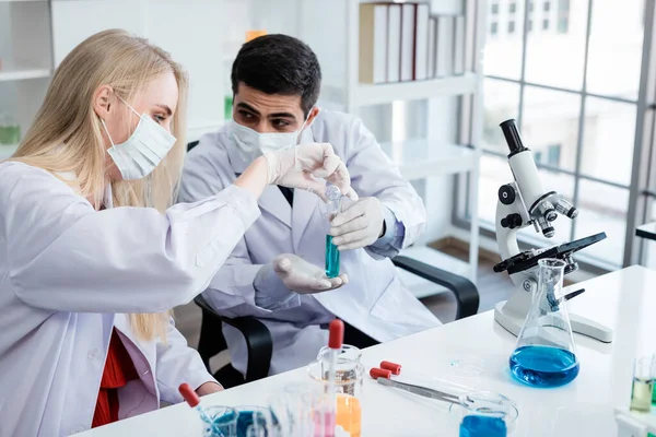 Two scientists are working holding looking at test tube with sample in a chemistry lab scientist or young female and male researcher are doing investigations in Laboratory analysis background