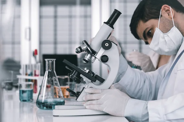 Científico Masculino Trabajando Mirando Microscopio Con Tubo Ensayo Muestra Investigador — Foto de Stock