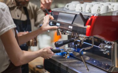 Barista makes coffee in the coffee machine another Barista teaches you to do it clipart