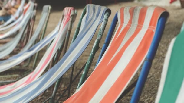 Les chaises longues sont soufflées par le vent sur une plage de galets, lentement à 4k — Video