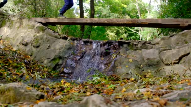 Turistas caminan a lo largo de un puente de madera sobre un río de montaña con agua clara . — Vídeo de stock