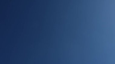 Modern yolcu uçağı çerçevenin ortasında, tepemizde uçuyor. Arka planda güzel mavi gökyüzü