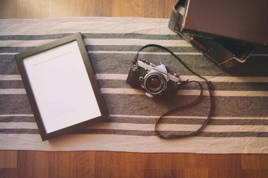 Eski kamera ve boş fotoğraf çerçevesi ahşap masada..