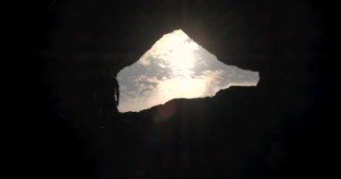 Erkek yürüyüşçü mağara yürüyüşü yapan açık hava yürüyüşçüsü siluetinden çıkıyor..