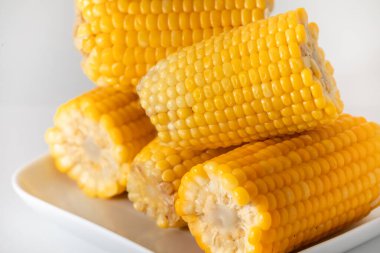 Bazıları, tuzlu ve tereyağlı, tavada pişirilmiş yumuşak, sıcak ve sarı mısır. Birlikte hizmet edip, beyaz bir tencereye istiflenmiş..