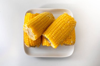 Bazıları, tuzlu ve tereyağlı, tavada pişirilmiş yumuşak, sıcak ve sarı mısır. Birlikte hizmet edip, beyaz bir tencereye istiflenmiş..