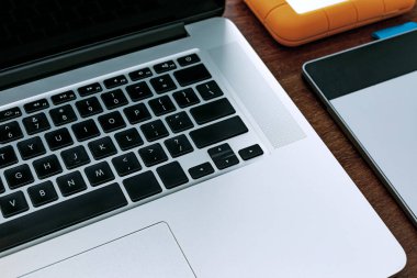 Bilgisayarın siyah ekranının görüntülenmesi, evde çalışacak bir cihaz, araştırma, ajanda, HD, cep telefonu, grafik tableti, kulaklık ve USB bellek. Tahta bir ofis masasının üstünde..