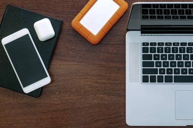 Bilgisayarın siyah ekranına bakmak, evde çalışmak için bir cihaz, araştırma, ajanda, HD, cep telefonu, kulaklık ve USB bellek. Tahta bir ofis masasının üstünde..