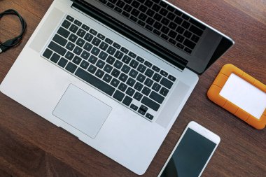 Bilgisayarın siyah ekranının görüntülenmesi, evde çalışacak bir cihaz, araştırma, ajanda, HD, cep telefonu ve USB bellek. Tahta bir ofis masasının üstünde..