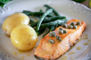 Güzel bir somon bifteği, kapari sosu, patates, sarımsak, maydanoz ve Fransız fasulyesi..