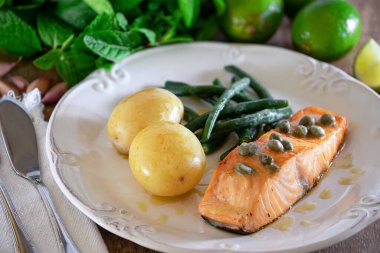 Güzel bir somon bifteği, kapari sosu, patates, sarımsak, maydanoz ve Fransız fasulyesi..