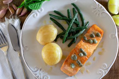 Güzel bir somon bifteği, kapari sosu, patates, sarımsak, maydanoz ve Fransız fasulyesi..