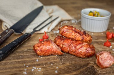 Ahşap tabakta ızgara Brezilya sosisi, yanında da kampanya sosu ve biber. Brezilya barbeküsü.