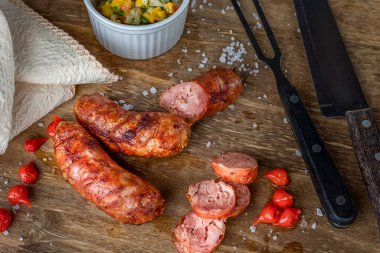 Ahşap tabakta ızgara Brezilya sosisi, yanında da kampanya sosu ve biber. Brezilya barbeküsü.