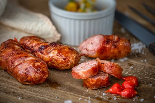 Grilled Brazilian sausage of ham on a wooden plate, accompanied by campaign sauce and pepper. Brazilian barbecue.