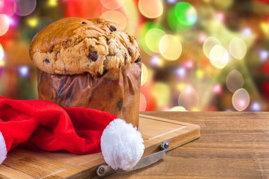 Çikolatalı panettone, Noel için geleneksel İtalyan tatlı pastası. Arka planda yanıp sönen ışıklar ve bulanık dekorasyonlar.