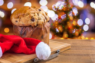 Çikolatalı panettone, Noel için geleneksel İtalyan tatlı pastası. Arka planda yanıp sönen ışıklar ve bulanık dekorasyonlar.