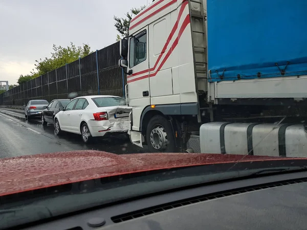 Araba olayı geçen araba karayolu üzerinde. Yağmurda binek otomobil kamyona çarpan