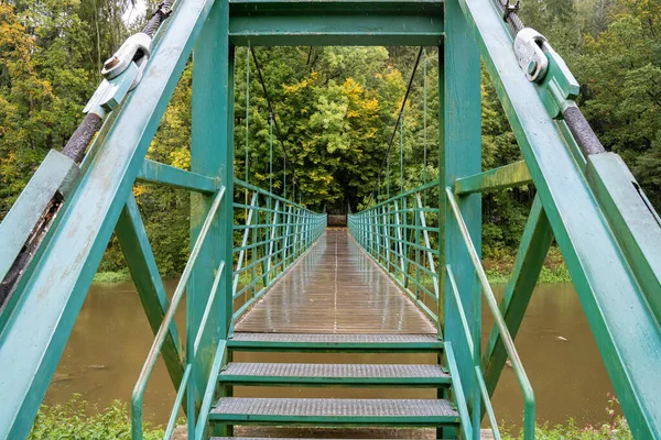 Hängebrücke im Herbst über den Fluss. grüne Brücke. — Stockfoto