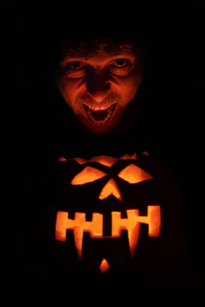 Страшное лицо, освещенное тыквой на Хэллоуин. Злой смех. Лицо человека — стоковое фото