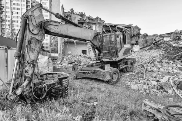 Koparka przed wyburzeniem starego budynku. Rekonstrukcja miasta. Czerń i biel — Zdjęcie stockowe