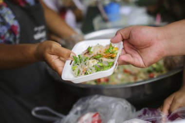 İnsancıllık kavramı : Mültecilerin ellerine açlığı hafifletmek için sadaka gıda ile desteklenmiştir : Beslenme Kavramları : Zengin bir adamdan yiyecek bağışlamayı teklif edilen el Paylaş