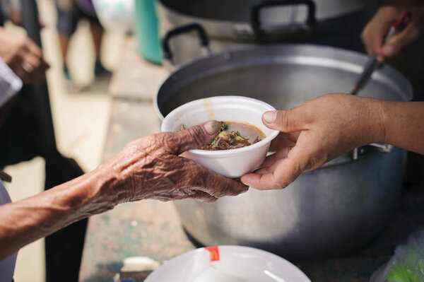 Рука нищих получает благотворительную пищу от других людей: Понятие гуманности: Руки беженцев получают помощь от благотворительной пищи, чтобы облегчить голод: Кормление концепций
