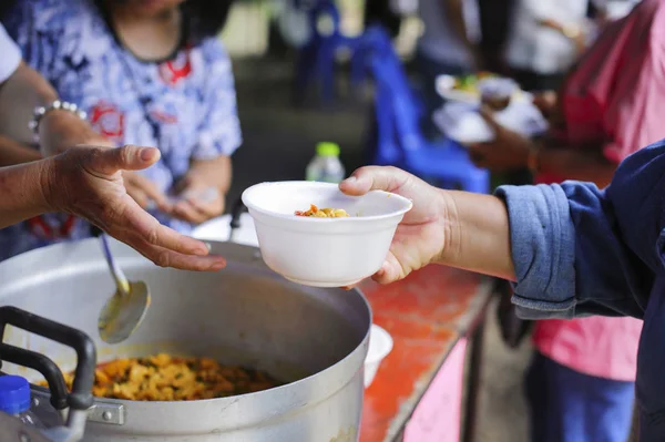 The concept of social sharing : Poor people receiving food from donations : Homeless people are helped with food relief, famine relief : volunteers giving food to poor people in desperate need