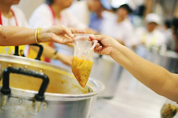 Hands of volunteers serves free food to the poor and needy in the city