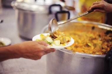 Ücretsiz yemek molalarına yardım etmeye gelen gönüllülerin elinden yemek kabul eden dilencilerin elleri.
