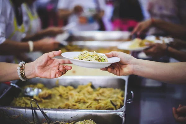 The donor gives warm food to the recipients with concern, donating food to the poor in Asian society : concept of sharing food to the poor