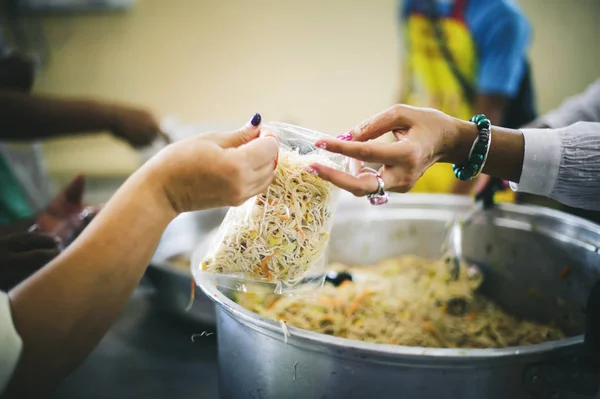 The donor gives warm food to the recipients with concern, donating food to the poor in Asian society : concept of sharing food to the poor