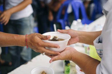 Toplumun birbirini paylaşma konsepti: bedava yemek molası vermeye gelen gönüllülerin ellerinden yemek kabul eden dilencilerin elleri.